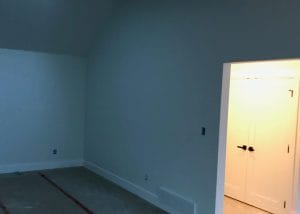 An unfinished room with skylight and a white door.