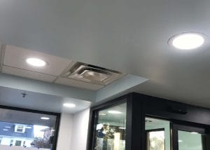 Interior of a modern building lobby with recessed lighting and an exposed ceiling panel.